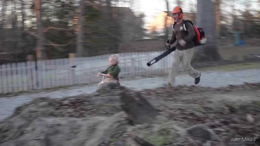 Father Pushes Son on Bike with Leaf Blower 