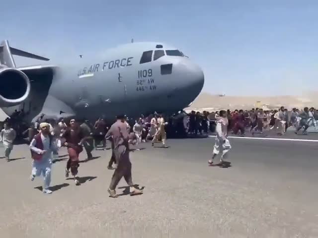 people cling to the landing gear as a C-17 is leaving Afghanistan